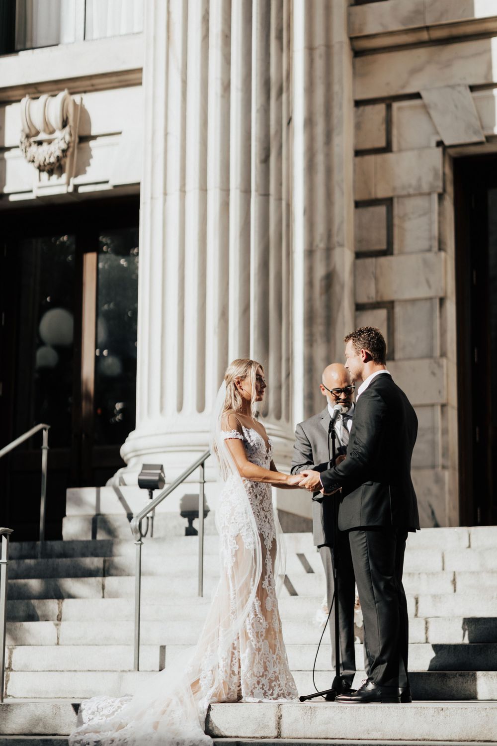 Outdoor wedding ceremony in front of historic building with white columns.