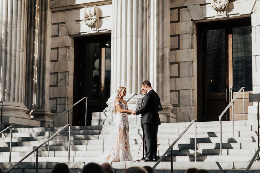 Wedding ceremony on white stone steps of neoclassical building.