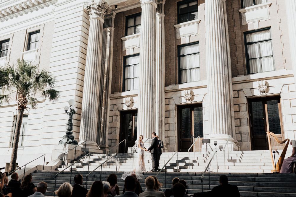 Wedding ceremony view from below showing historic building's columns and palm tree.