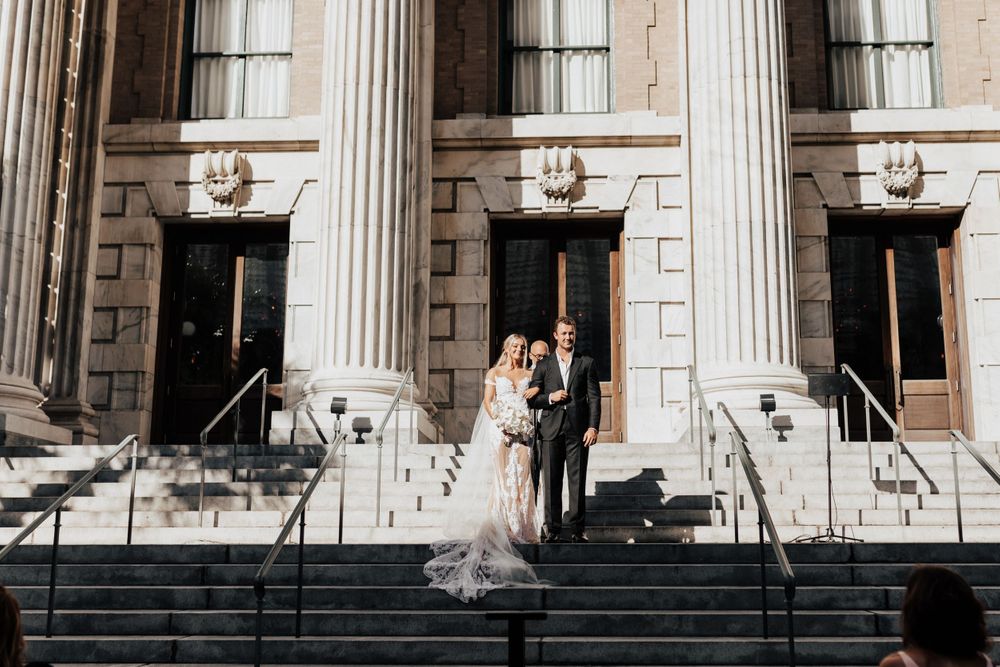 An elegant wedding ceremony framed by towering white columns and stone steps.