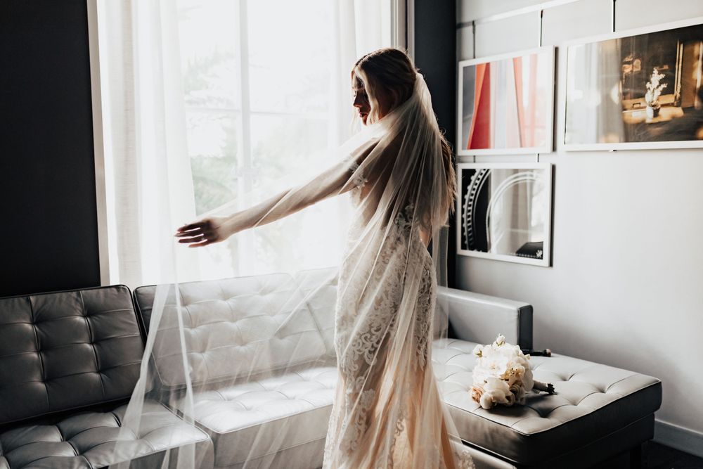 An ethereal bridal moment captured in natural light with flowing lace gown and veil.