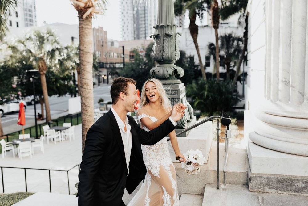 A celebratory moment on grand steps with palm trees and columns in an urban setting.