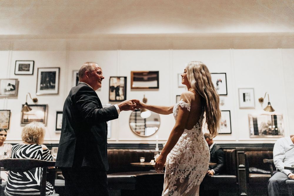 A couple interacts during what appears to be a wedding celebration in a restaurant setting.