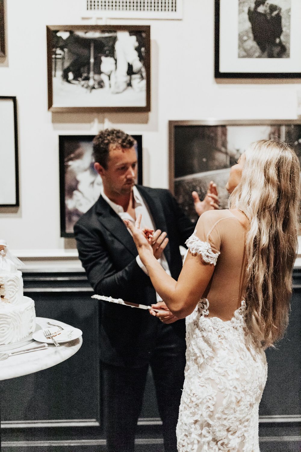 A couple shares a moment near their wedding cake in a restaurant decorated with vintage photographs.