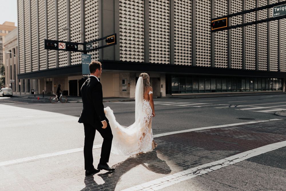 A wedding couple walking down a modern city street with dramatic shadows.