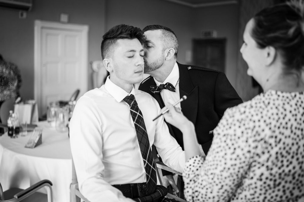 groom kisses groom in a suit at the elvetham hotel
