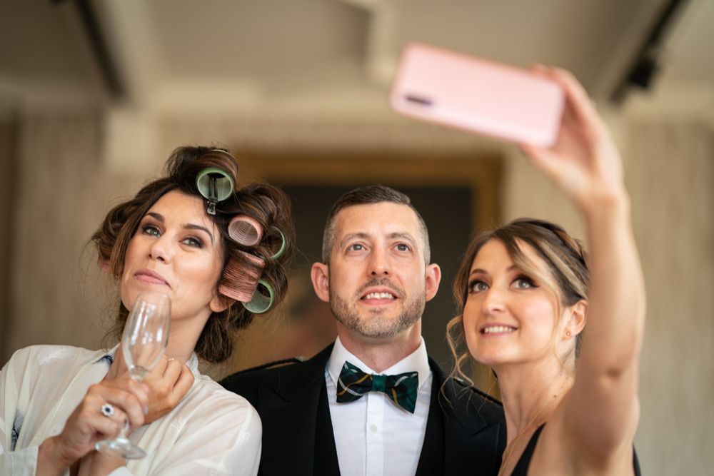 groom poses for bridesmaid selfie