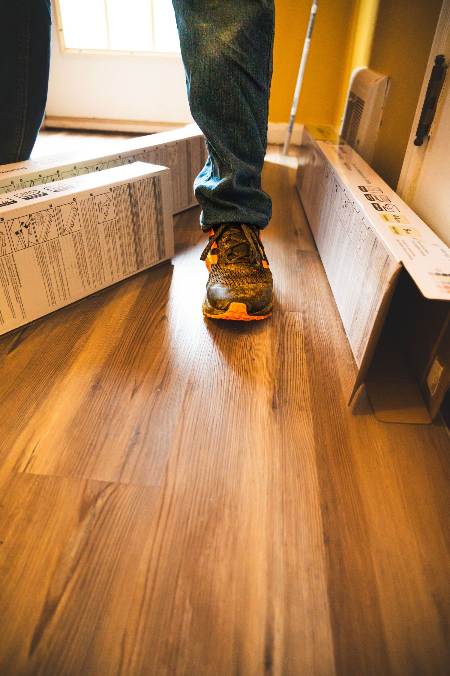 Orange athletic shoe on hardwood floor during renovation.