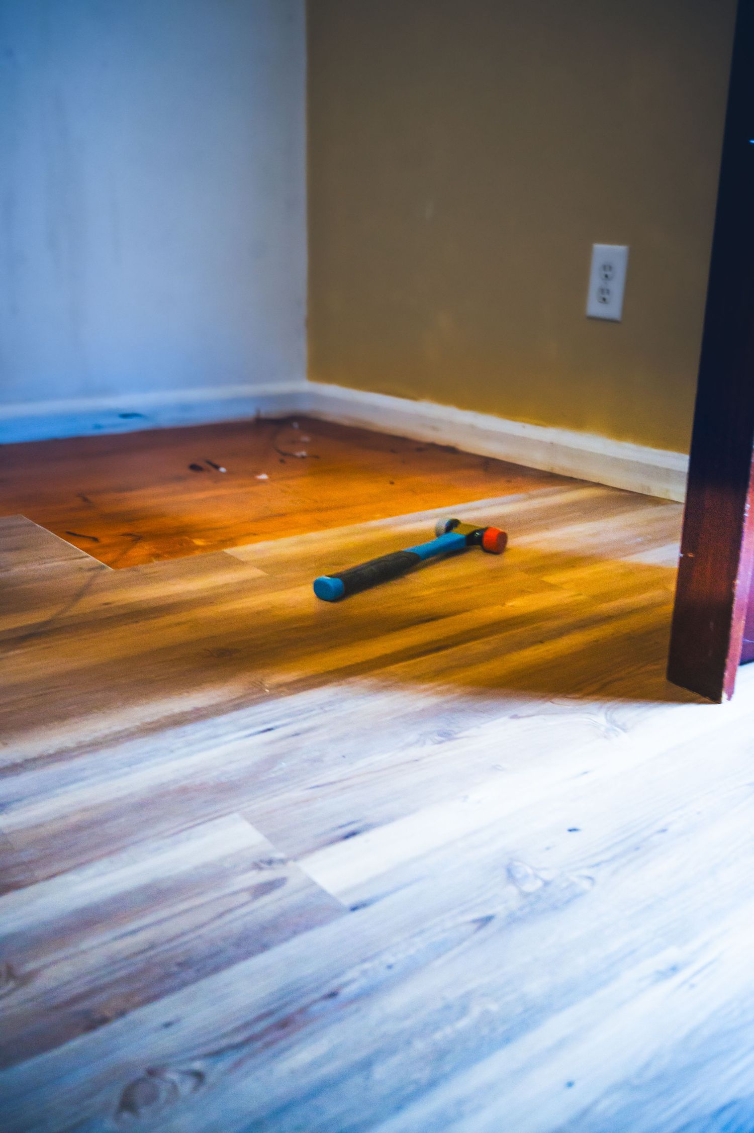 Blue roller tool lying on partially finished hardwood flooring.