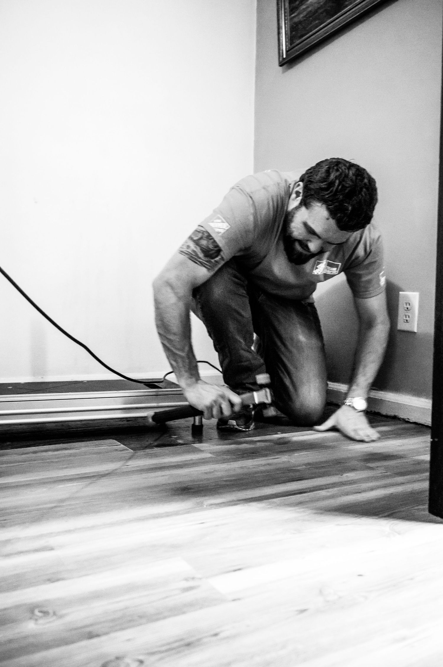 Person working on floor installation with tools.