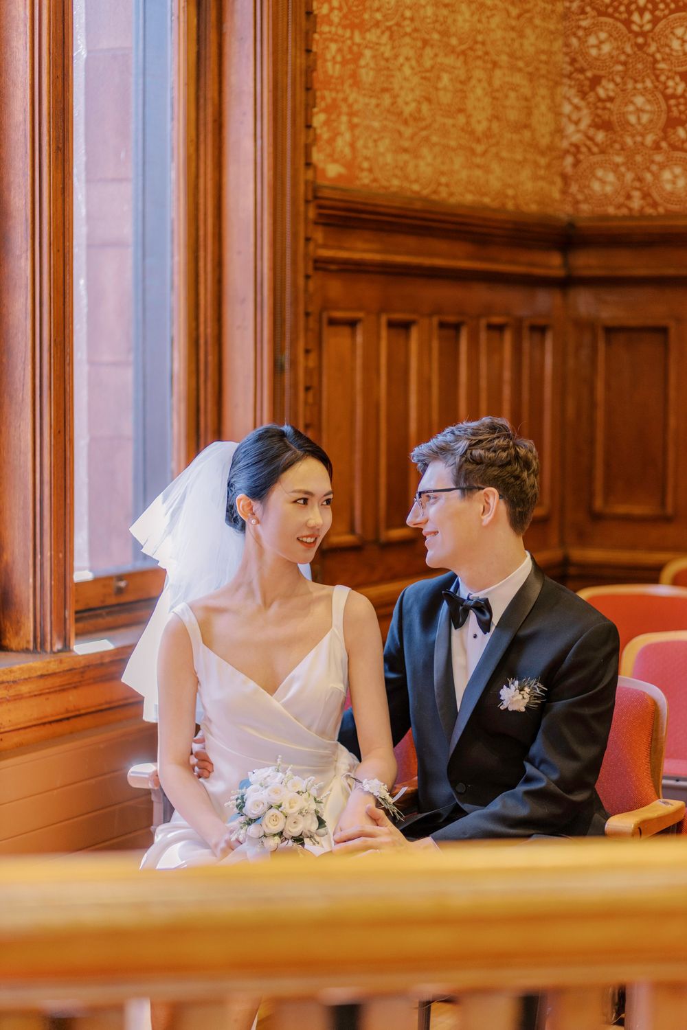 A tender moment captured in an elegant wood-paneled room with vintage wallpaper.