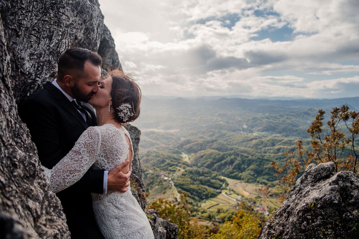 An intimate embrace against dramatic mountain scenery with valley views below.