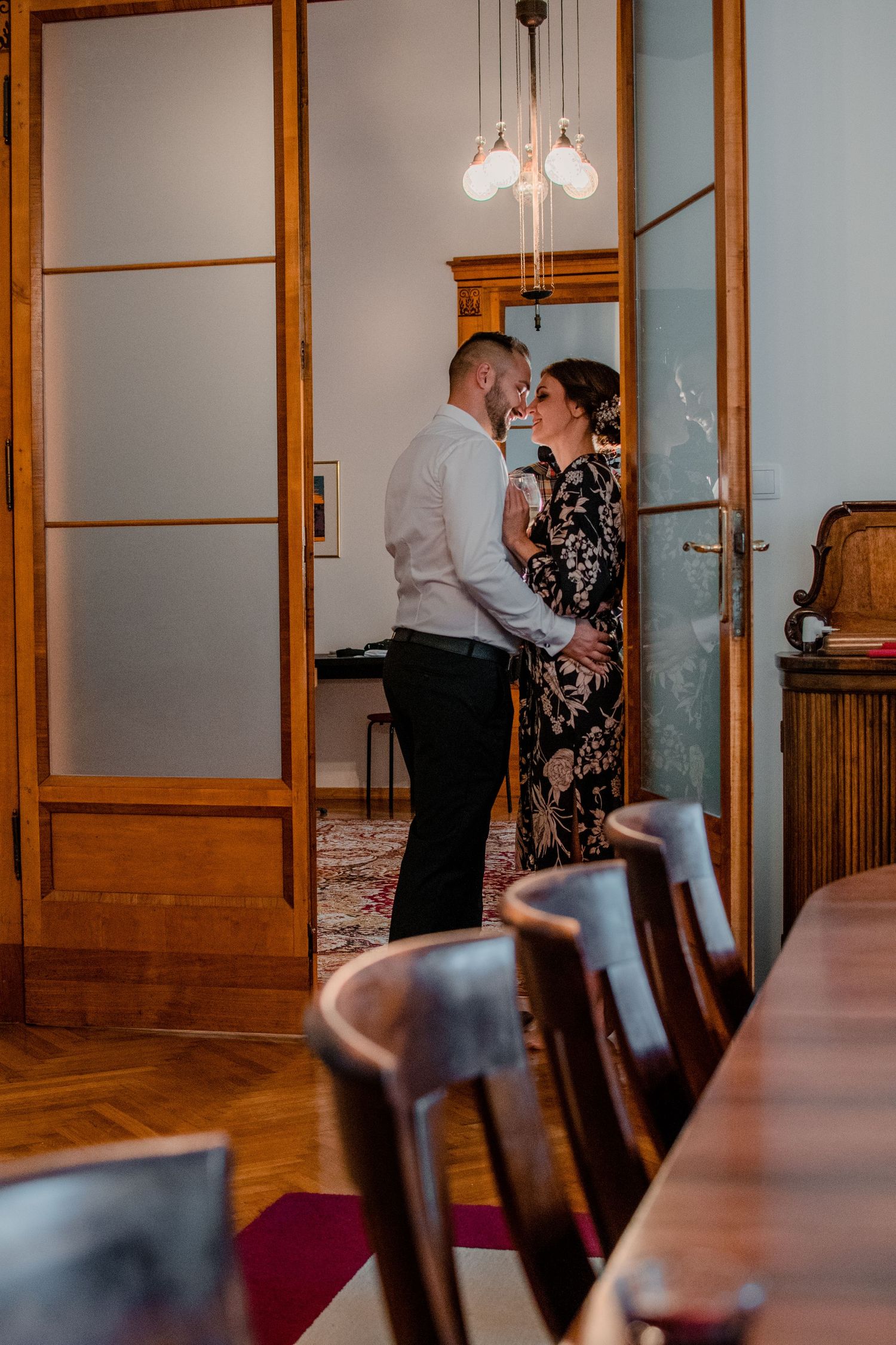 Couple sharing an intimate moment in an elegant room with wooden furniture.