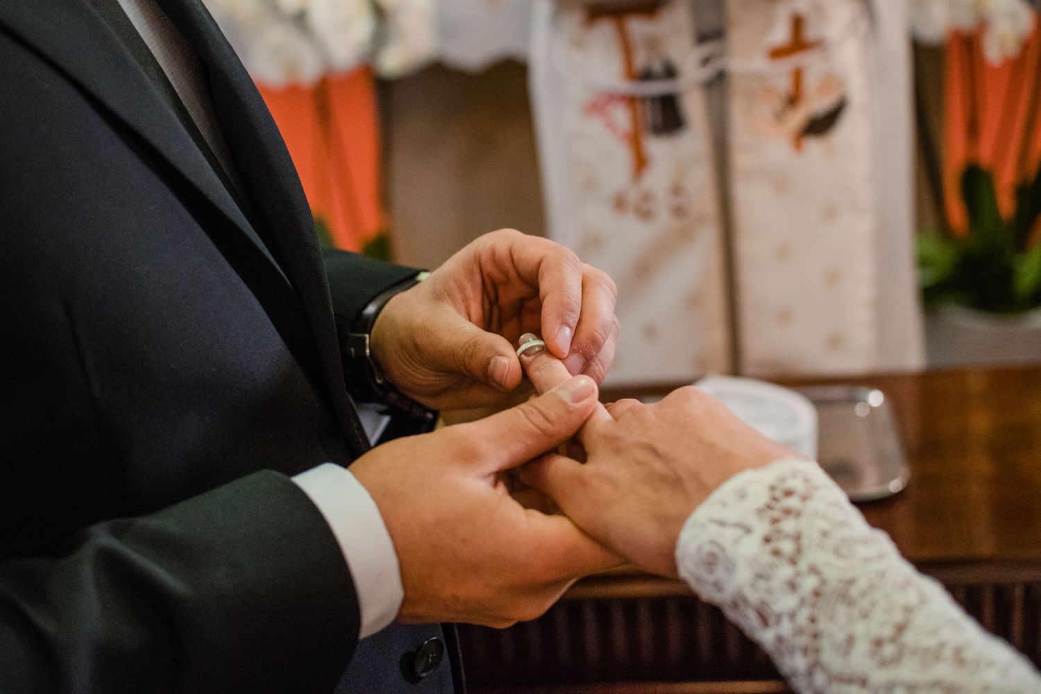 Close-up of hands exchanging rings during wedding ceremony.