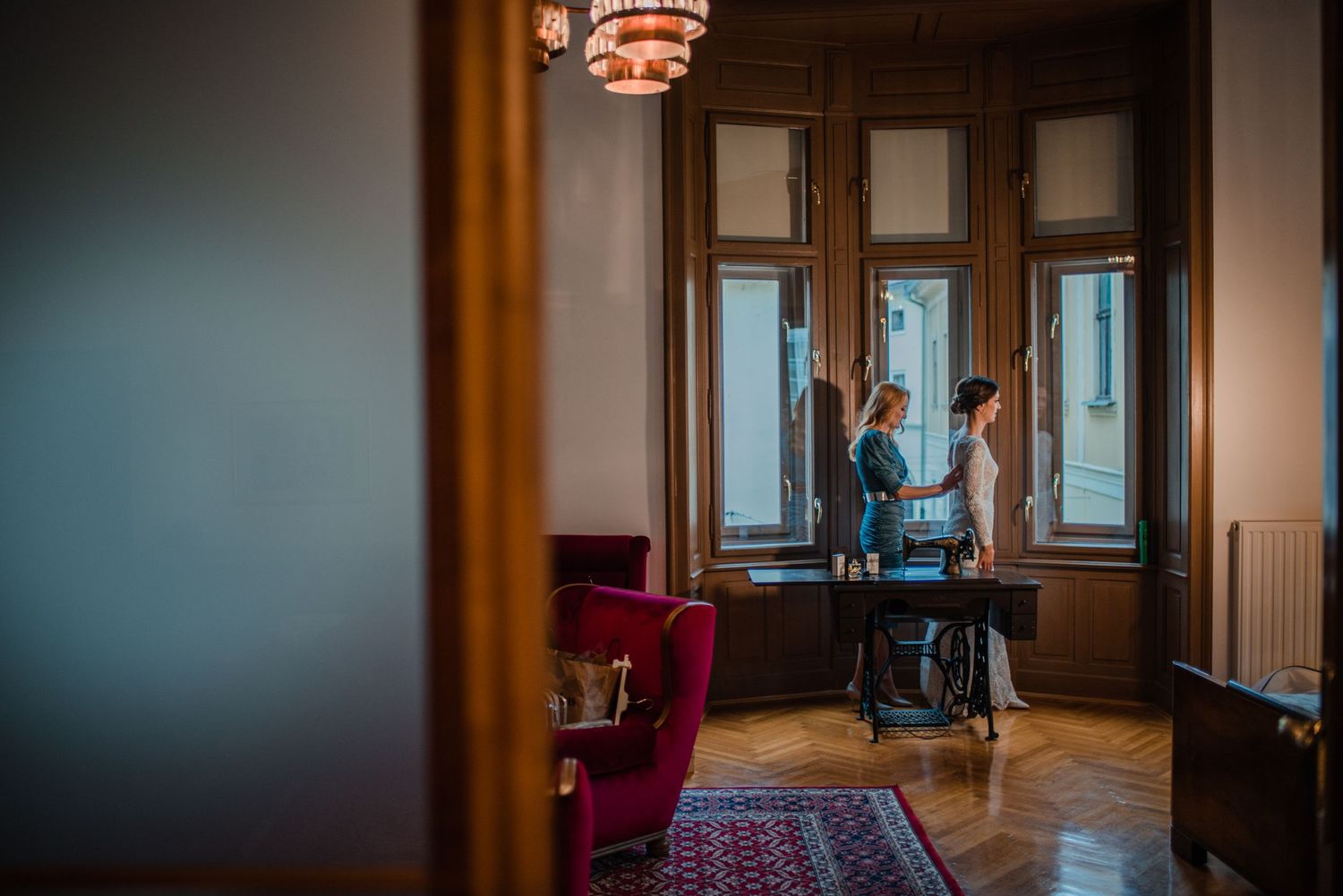 A dimly lit elegant room with large windows and vintage furniture.