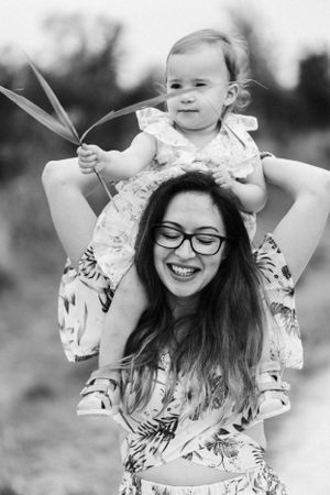 A joyful black and white portrait of a parent and child playing together outdoors in summer.