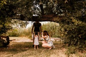 Family enjoying quality time together under a rustic wooden archway in a natural outdoor setting at sunset.