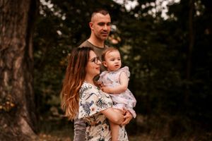 A serene family portrait taken in a wooded setting during golden hour.