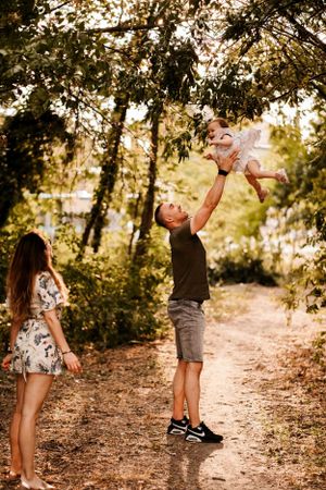 A playful moment captured on a wooded trail as a child is lifted high into the air.