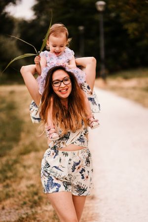 Joyful piggyback ride moment captured on a sunny path surrounded by nature.