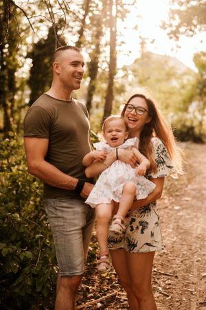 A playful family moment captured during golden hour in a wooded setting.