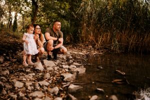 A family shares a tender moment together by the water's edge during golden hour.