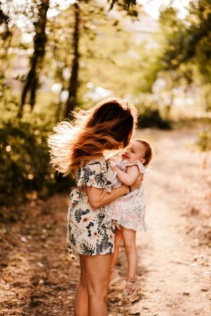 A tender embrace shared between two people on a sunlit forest path.