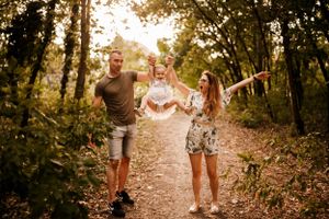 A joyful family walks together on a sunlit forest path during golden hour.