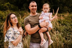 Summer family portrait in a field with coordinated casual outfits.