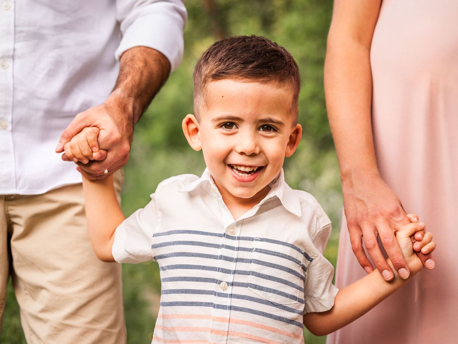 child holding parents hands in striped shirt