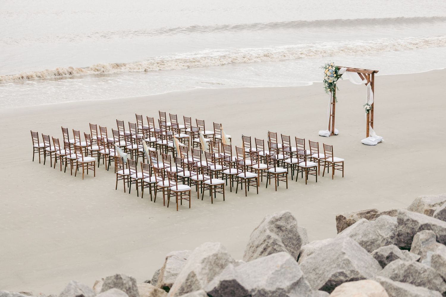 Beach ceremony site with empty chairs and arch