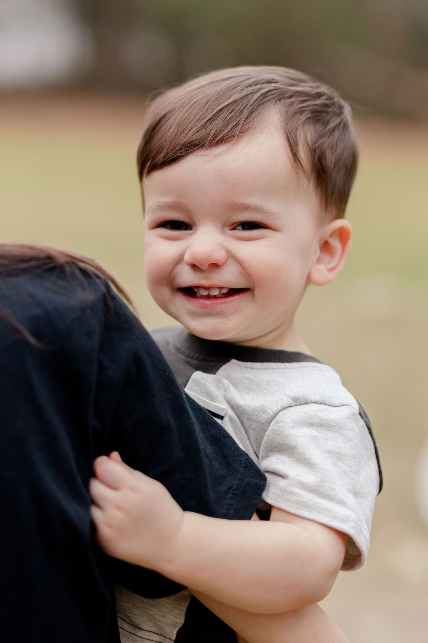 A joyful expression as a small child hugs someone while wearing a two-toned shirt.
