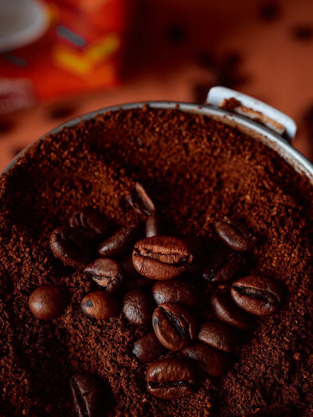 Ground coffee and whole beans in a coffee grinder viewed from above.