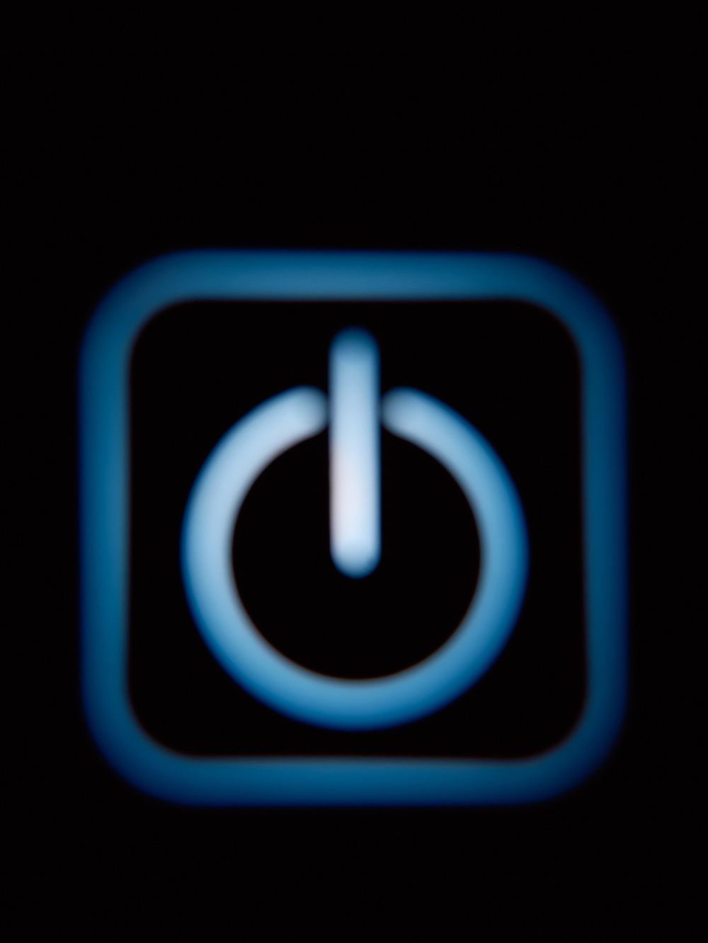 Glowing blue power button icon against black background.