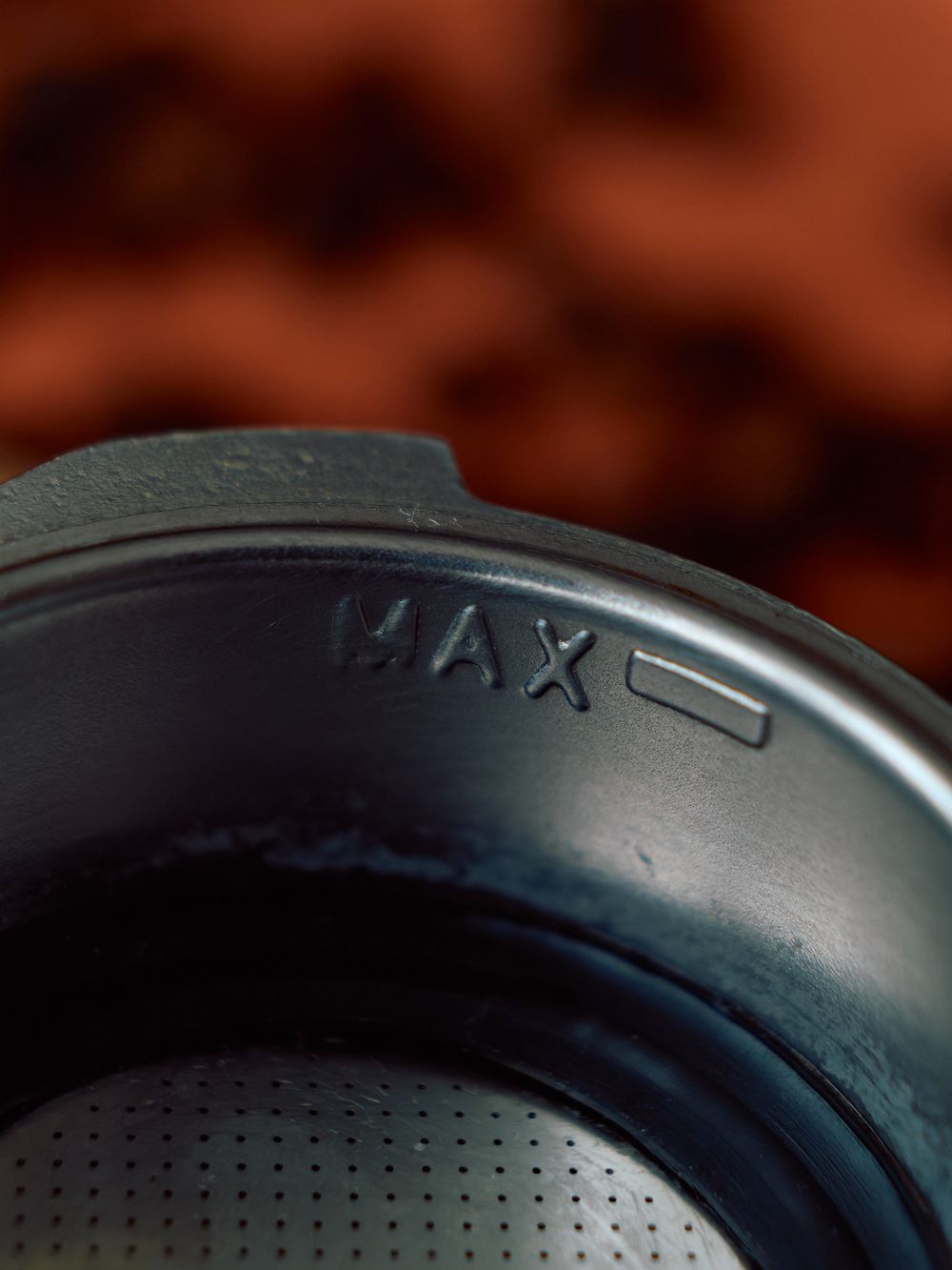 Close-up of MAX level marking on metal coffee grinder container.