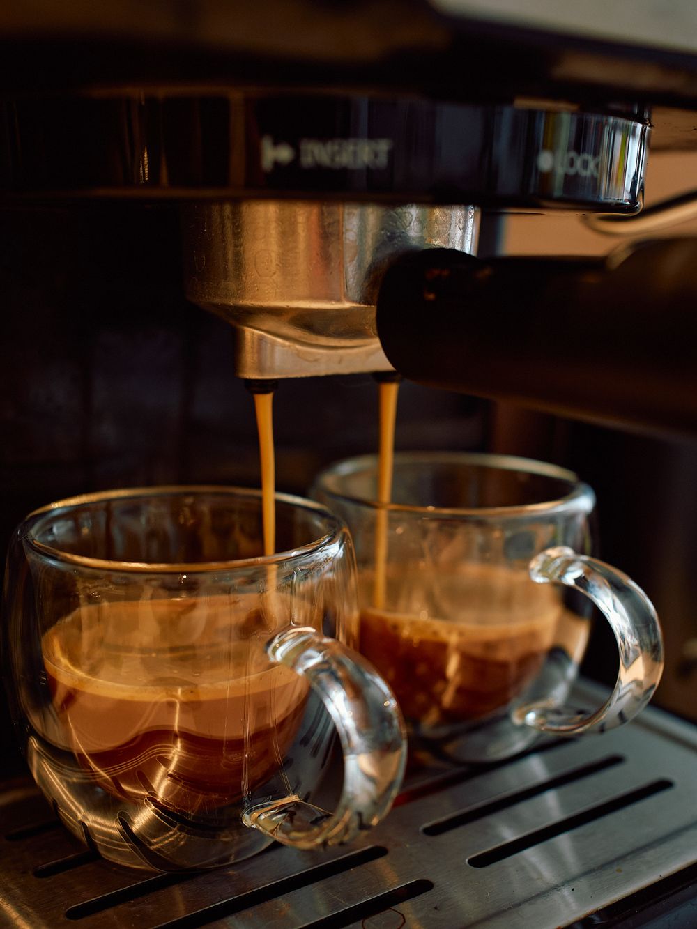 Espresso machine brewing coffee into two glass cups simultaneously.
