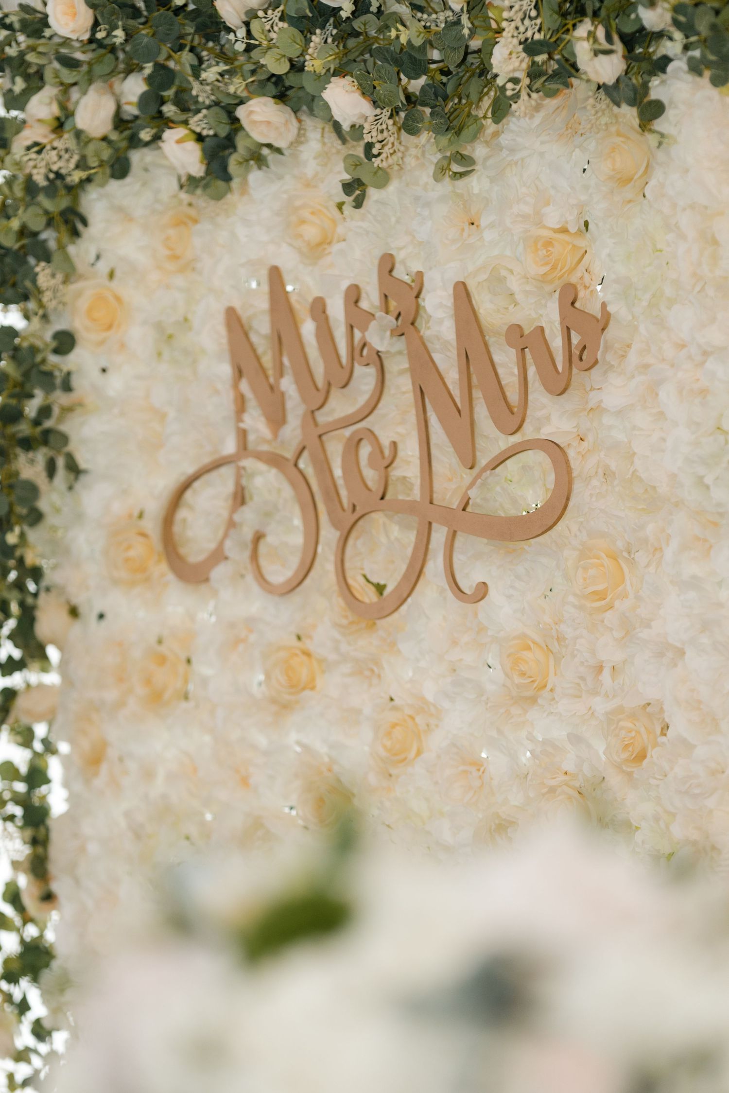 Elegant 'Mr & Mrs' wedding sign decorated with white flowers and greenery.