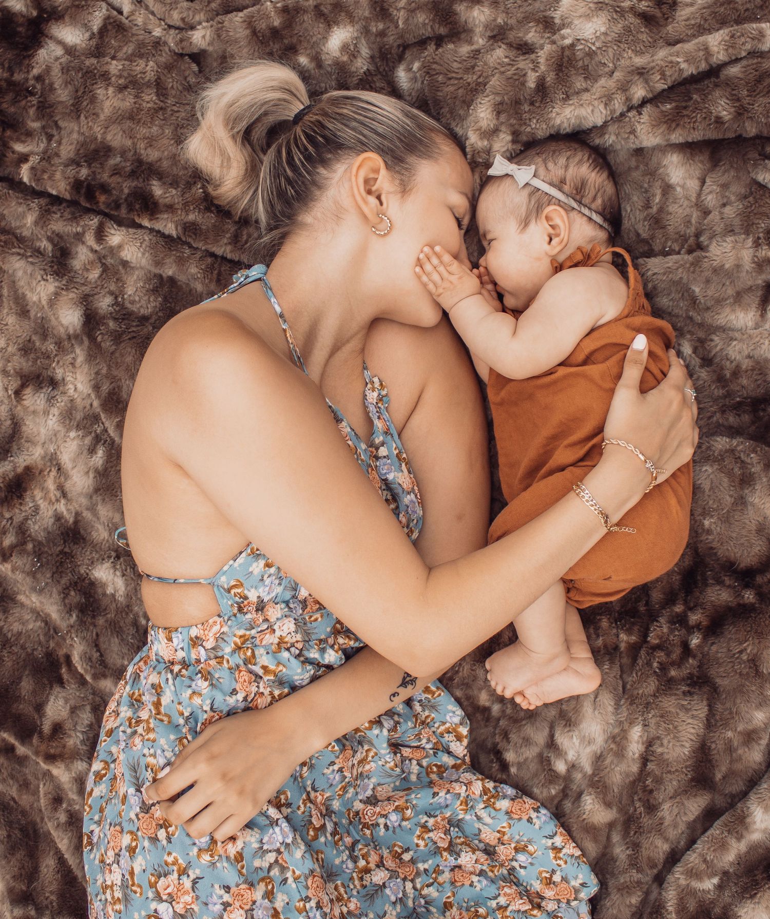 mom and baby girl, laying on a blanket, face to face, baby touching mom's face, loving and emotive moment of connection.