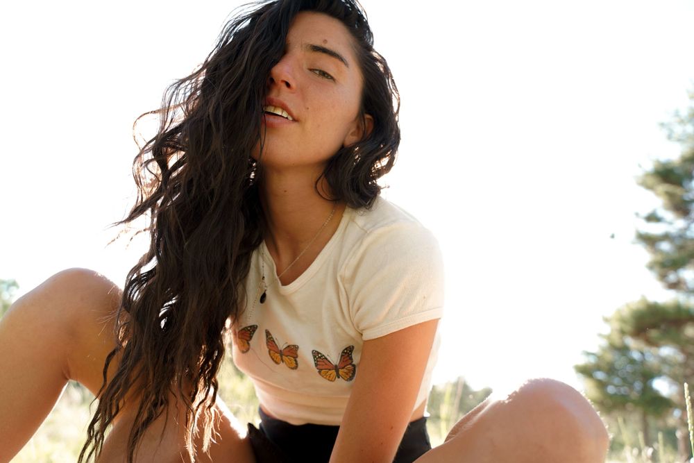 Candid outdoor portrait of someone in a butterfly t-shirt enjoying summer sunshine.