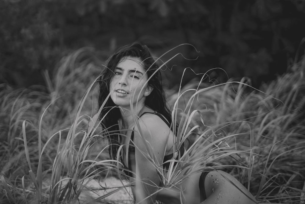 Portrait of a person sitting in tall grass in black and white.