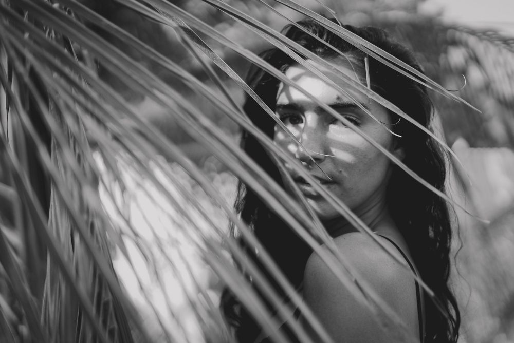 Artistic black and white portrait through palm fronds.