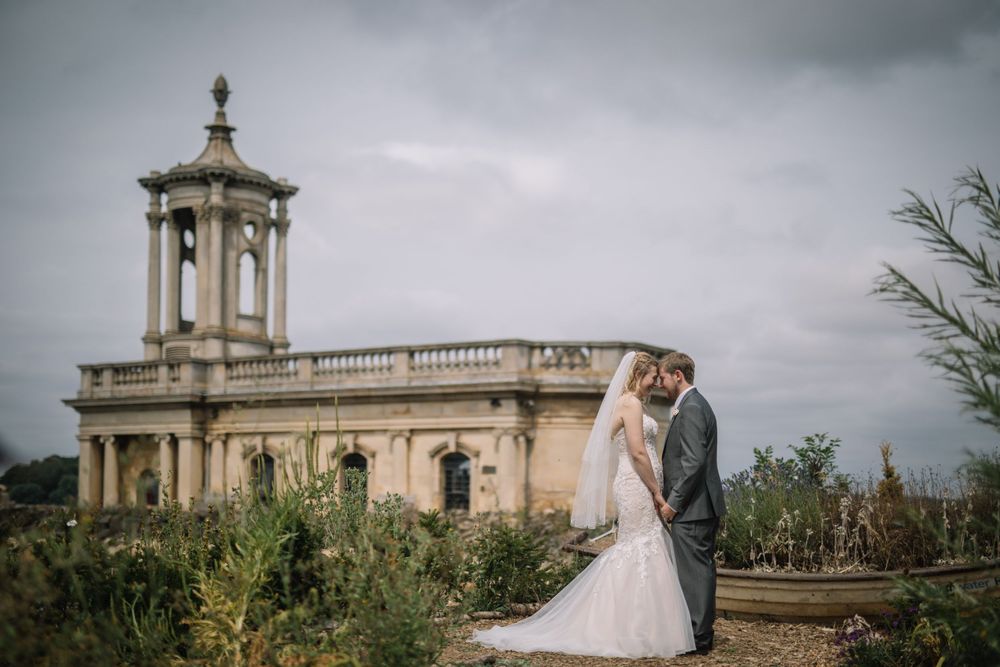 Romantic wedding portrait in front of a historic stone church under moody skies.
