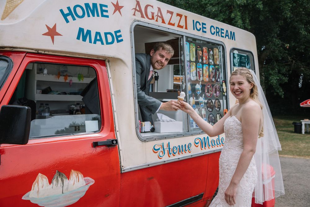 Newlyweds get ice cream from a vintage red and white ice cream truck.