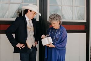 Two individuals engaged in discussion while standing outside a building with windows.