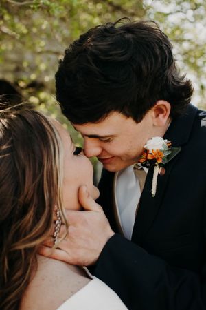 Romantic wedding portrait showing gentle embrace with soft golden light filtering through trees.