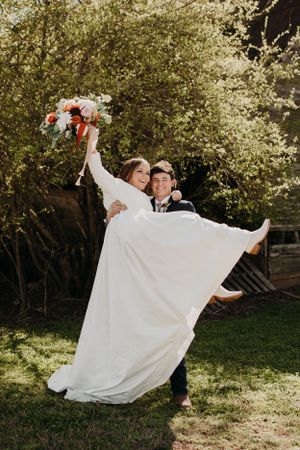 A candid wedding moment captured outdoors with flowing white dress.