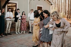 Friends enjoying dance moves at outdoor celebration while guests watch and cheer.