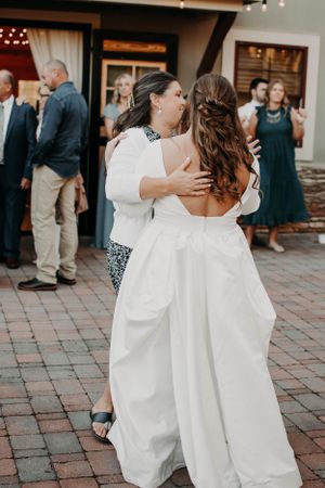 Two guests dance together at an outdoor wedding reception on a brick patio.