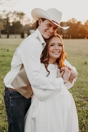 Couple in western attire sharing joyful moment during sunset photo session.