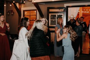 Party guests dancing and celebrating in a rustic indoor venue with string lights.